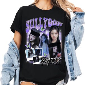 May include: Black t-shirt featuring a graphic design with the name "SULLYOON" in a purple, stylized font. The design includes images of a person, butterflies, and the word "NMIXX" in a cursive font.