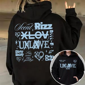 May include: Black hoodie with light blue text including "Scent Rizz", "XLOV", and "UNLOVE". The design features hearts and stars. A smaller image of the hoodie is in the lower right corner. The hoodie has a hood and a front pocket.