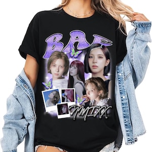 May include: Black t-shirt featuring a graphic design with the word "BA" in purple glitter and images of several women. The design includes butterflies and the word "Otmixx" in white script.