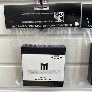 May include: A black box with a white label that reads "BRITISH BROADCASTING CORPORATION MASTER SERIES MICROCOMPUTER" and "HDMI TO TV" and "SCART FROM BBC". The box is labeled as a "MICROCOMPUTER SYSTEM BBC MICRO / BBC MASTER HDMI CONVERTER".