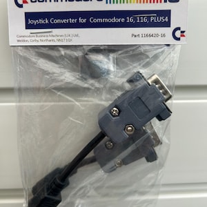 Può includere: Un convertitore per joystick grigio e nero per i computer Commodore 16, 116 e PLUS4. La confezione include il testo "Joystick Converter for Commodore 16, 116, PLUS4" e "Part 1166420-16".