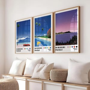 Op de afbeelding: Drie ingelijste prints met een retro-esthetiek. Elke print toont een andere sc&egrave;ne met een blauw, paars en roze kleurenschema. De prints zijn getiteld "Hiroshi Nagai" en bevatten de tekst "Tokyo 1975".