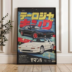 Puede incluir: Póster enmarcado con un diseño retro japonés, con dos coches deportivos clásicos en blanco y negro. El póster incluye texto japonés en amarillo y rojo, sobre un fondo azul y rojo. Los coches son el elemento central de la obra.