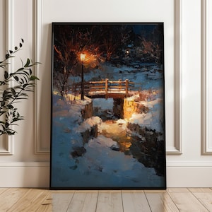 May include: A framed painting depicts a winter landscape with a wooden bridge over a snow-covered stream. A lamppost illuminates the bridge and surrounding snow. The artwork is in a black frame and leans against a white wall.