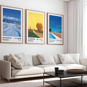Op de afbeelding: Drie ingelijste kunstprints met een minimalistisch ontwerp. De prints tonen een besneeuwd berglandschap, een geel veld met een boom en een zwembad met een vliegtuig dat erboven vliegt. Elke print heeft de tekst "HIROSHI NAGAI" en een datum.
