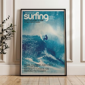 May include: Framed vintage poster with a surfing theme. The poster features the text "International Surfing" and "You can learn to surf, 10 tips make it easier." A surfer rides a wave. The poster also lists locations like Hawaii and California.