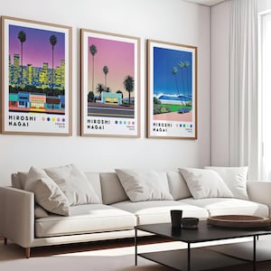 Op de afbeelding: Drie ingelijste prints van stadsgezichten met een retro 80s-esthetiek. De prints tonen een roze en paarse zonsondergang, een roze en blauwe zonsondergang en een blauwe oceaan sc&egrave;ne. Elke print heeft de tekst "HIROSHI NAGAI" en "TOKYO 1972" onderaan.