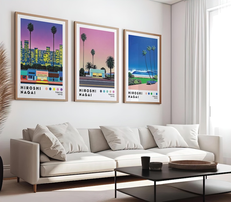 Op de afbeelding: Drie ingelijste prints van stadsgezichten met een retro 80s-esthetiek. De prints tonen een roze en paarse zonsondergang, een roze en blauwe zonsondergang en een blauwe oceaan sc&egrave;ne. Elke print heeft de tekst "HIROSHI NAGAI" en "TOKYO 1972" onderaan.