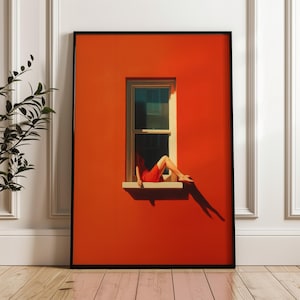 Peut inclure: Une impression d'art encadrée représentant une personne en robe rouge se prélassant dans une fenêtre. L'œuvre est placée contre un mur orange vif, avec une longue ombre projetée par la fenêtre. L'impression est dans un cadre noir et est exposée sur un sol en bois.