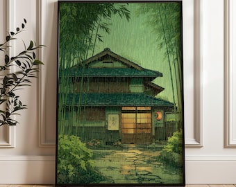 May include: Framed art print depicting a traditional Japanese house in a bamboo forest during a rainstorm. The house features a green tiled roof and a warm interior glow. The artwork uses a muted green and brown colour palette.
