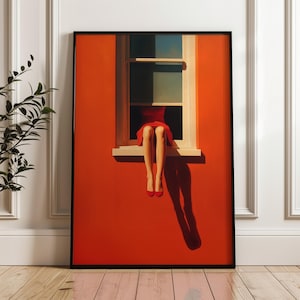 Peut inclure: Impression artistique encadrée en noir, représentant une personne en robe rouge assise dans une fenêtre. L'œuvre est posée sur un mur orange vif, avec les jambes et les chaussures rouges de la personne visibles.