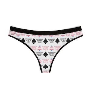 May include: White thong underwear with a black waistband. The underwear features a repeating pattern of the text "Worship Black Men" and "Feminize White Boys", along with spade symbols and geometric shapes.
