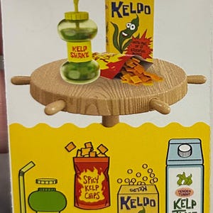 May include: A whimsical illustration featuring a green Kelp Shake, a box of Keldo cereal, and a bag of Spicy Kelp Chips. The Kelp Shake is in a unique bottle with a straw. The Keldo box has a cartoon kelp character. The chips are in a red bag.