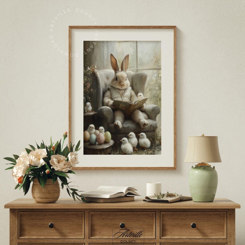 May include: A framed print depicts a rabbit in a waistcoat reading a book in a chair, surrounded by chicks and Easter eggs. The artwork has a vintage, pastel color palette, with a wooden frame. The scene evokes a cozy, springtime atmosphere.