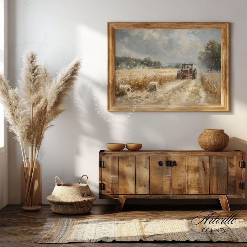 Puede incluir: Una pintura de paisaje enmarcada representa un tractor rojo en un campo, con un mueble de madera y objetos decorativos en primer plano. El mueble es de madera y tiene dos puertas. A la izquierda hay un jarr&oacute;n grande con plantas altas y secas.
