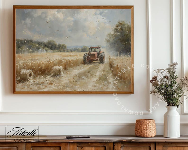 Puede incluir: Una pintura de paisaje enmarcada representa un tractor rojo cosechando trigo en un campo bajo un cielo nublado. La obra de arte presenta balas de heno y p&aacute;jaros, con una c&aacute;lida paleta de colores marrones, amarillos y azules. La pintura est&aacute; en un marco de madera.