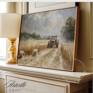Puede incluir: Una pintura de paisaje enmarcada representa un tractor rojo en un campo de trigo bajo un cielo nublado. La obra de arte, con un marco de madera, presenta balas de heno y &aacute;rboles. La pintura est&aacute; apoyada en una superficie blanca, con el texto "Artville County" visible.