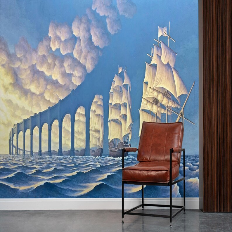 Puede incluir: Un sill&oacute;n de cuero marr&oacute;n con un marco de metal negro se encuentra frente a una pintura surrealista que representa barcos navegando bajo un puente en un cielo azul con nubes blancas.