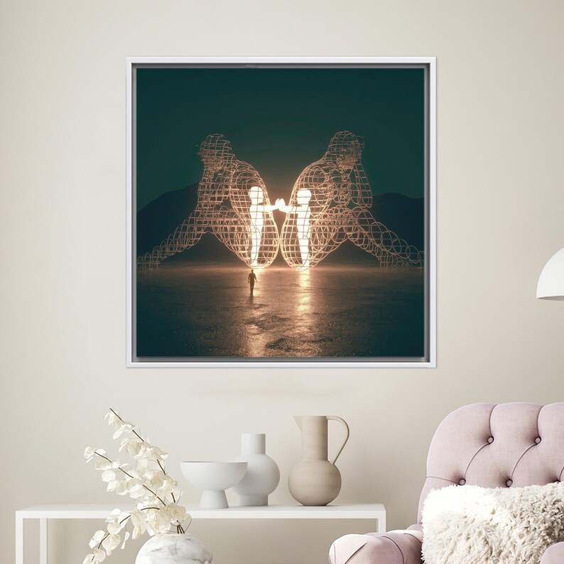 Op de afbeelding: Een ingelijste kunstdruk met een surrealistisch landschap. Twee grote draadfiguren zitten rug aan rug, verlicht door een warme gloed. Een klein figuur staat op de voorgrond, naar het licht kijkend. Het kunstwerk is geplaatst tegen een donkere hemel.