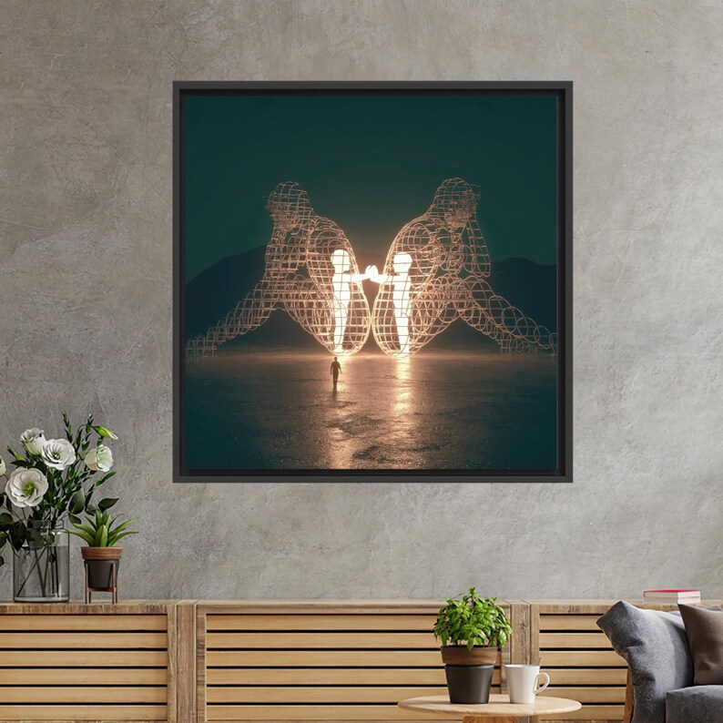 Op de afbeelding: Ingelijste kunstdruk met een surrealistisch landschap met twee draadfiguren die elkaar aankijken en verlicht zijn. Een kleine figuur staat tussen hen in, met een donkerblauwe lucht en bergen op de achtergrond.