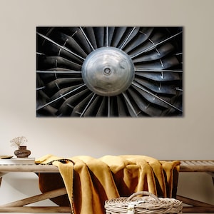 Può includere: Primo piano di una turbina di motore aeronautico metallica. L'immagine mostra l'intricato design delle pale che si irradiano da un mozzo centrale. Le pale sono di colore grigio scuro e il mozzo è di colore argento. Primo piano.