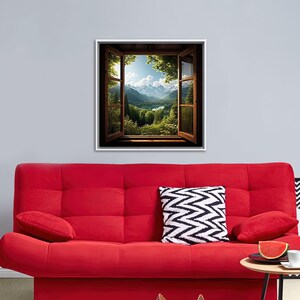 May include: A framed print of a window looking out onto a mountain landscape with a lake. The window is open and the view is of a green valley with mountains in the distance. The sky is blue and there are clouds in the sky.