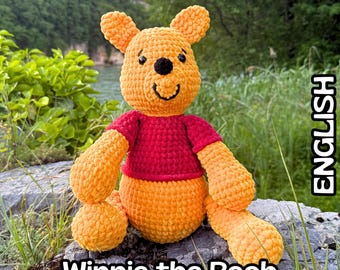 Op de afbeelding: Een haakpatroon PDF voor een knuffelbeer. De beer is geel met een rond hoofd, kleine oortjes en een zwarte neus. Het draagt een rood shirt en heeft een textuur van garen. De tekst luidt Crochet Pattern, Winnie the Pooh en ENGLISH.
