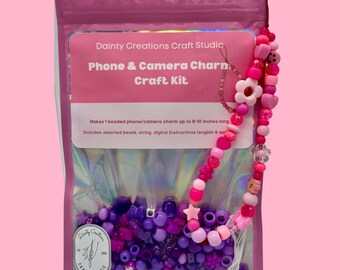 May include: A pink craft kit for making beaded phone and camera charms. The kit includes assorted beads, string, and instructions. The finished charm can be up to 8-10 inches long. A beaded charm with pink and purple beads is shown.
