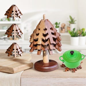 May include: Set of four wooden pot holders shaped like Christmas trees. The pot holders are stacked on top of each other, with the largest one at the bottom. The pot holders are made of natural wood and have a rustic look. A green pot is sitting on top of the pot holders.
