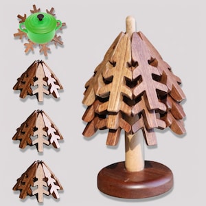 May include: A wooden Christmas tree ornament with a brown and light brown wood finish. The tree is made of interlocking pieces that can be folded and unfolded. The ornament is sitting on a wooden base.