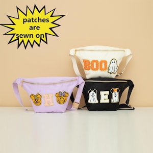 May include: Three fanny packs with different embroidered patches. The first is white with "BOO" and a ghost. The second is purple with "HOME" and two Mickey Mouse heads. The third is black with "ME" and two ghosts.