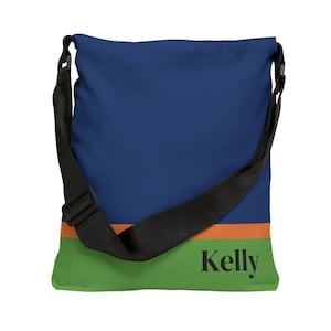 May include: A blue, green, and orange canvas tote bag with a black adjustable strap. The bag has the name "Kelly" printed on the front.
