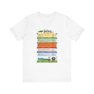 May include: White t-shirt with a colorful fishing cheat sheet graphic. The graphic includes a fish, a fishing rod, and text that says "Fishing Cheat Sheet".
