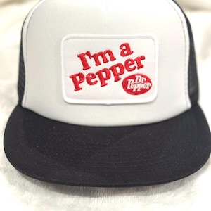 May include: White and black trucker hat with a red and white embroidered patch that says "I'm a Pepper" with the Dr Pepper logo below it.