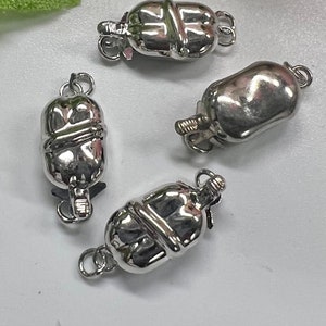 May include: Four silver-toned metal clasps for necklaces or bracelets. Each clasp has a rounded, barrel-shaped design with a decorative groove.