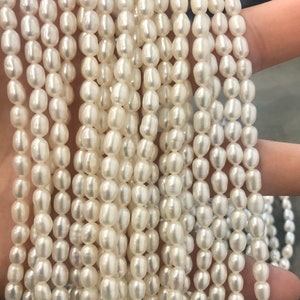 May include: Strands of creamy white oval pearls. The pearls are strung together, creating a cascading effect. The pearls have a smooth, lustrous surface, reflecting light. The overall appearance is elegant and classic, suitable for jewelry making.