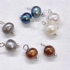 May include: Assortment of pearl beads with silver jump rings and silver bead caps. The pearls are in various colors, including white, brown, gray, and black.