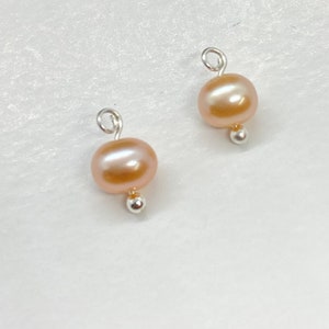 May include: Two peach-colored pearl beads with silver jump rings and silver bead caps.
