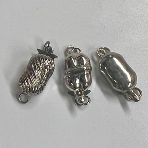 May include: Three silver-toned clasps for necklaces or bracelets. The clasps are different styles, one is a twisted design, one is a smooth oval, and one is a textured oval.