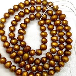 May include: Strand of lustrous, golden-brown freshwater pearls. The oval-shaped beads are strung together, showcasing a warm, metallic sheen. The pearls vary slightly in size and shape, creating a natural, organic look. Ideal for jewelry making.