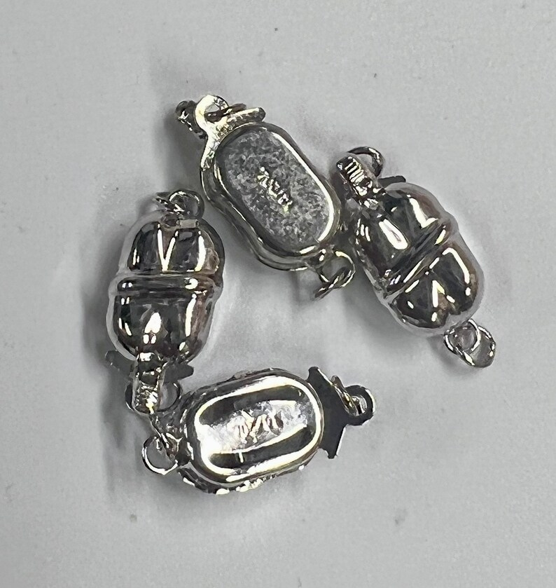 May include: Three silver-toned magnetic clasps for jewelry making. The clasps are oval-shaped with a textured surface and have a small loop on one end. The clasps are marked with the text "925".