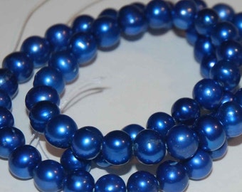 Puede incluir: Una hebra de cuentas de perlas azules. Las cuentas son redondas y tienen un brillo metálico.