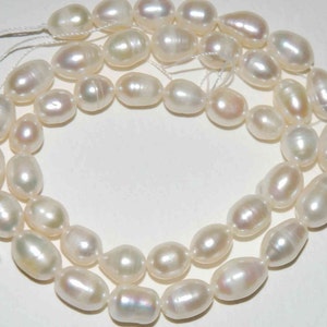 May include: A strand of white freshwater pearls, each pearl is oval shaped and has a smooth, lustrous surface.