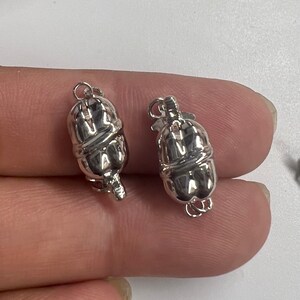 May include: Two silver-toned metal clasps for necklaces or bracelets. Each clasp is shaped like a pumpkin with a smooth, shiny finish.