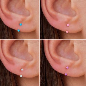 Może przedstawiać: Cztery zdjęcia przedstawiające przekłute uszy z małymi, okrągłymi kamieniami szlachetnymi. Kamienie szlachetne są w różnych kolorach: jasnoniebieskim, różowym, białym i fioletowym. Każde zdjęcie przedstawia dwa przekłucia na uchu, z kamieniami szlachetnymi w płatku ucha.