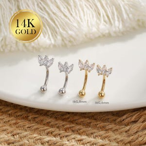 May include: Four curved eyebrow rings. Two are silver-toned with clear, marquise-cut stones in a floral design. The other two are gold-toned with similar stones. The text "14K GOLD" is in a gold circle. The gauge sizes are 16G, 8mm and 16G, 6mm.