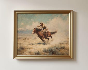 May include: A framed Western-themed painting depicts a cowboy on a galloping brown horse. The artwork, set in a desert landscape with mountains, features a gold-colored frame. The cowboy wears a hat and is riding through a cloud of dust.