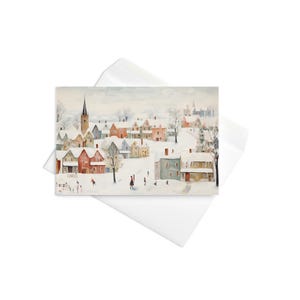 以下が含まれることがあります： 雪に覆われた家と教会の尖塔がある冬の村の風景が描かれたグリーティングカード。水彩画は雪の中を歩く人々を描いています。カードは白い封筒の中に入っています。