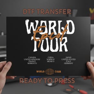 May include: Black rectangular DTF transfer with the words "WORLD EPIC TOUR" in white and orange. Below are lists of countries. The words "READY TO PRESS" are at the bottom.