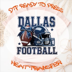 May include: A white t-shirt design featuring a football, helmet, and the text "DALLAS FOOTBALL" in blue. The design includes a football with a blue bow, a blue helmet, and stars. The words "DTF READY TO PRESS" and "HEAT TRANSFER" are also visible.